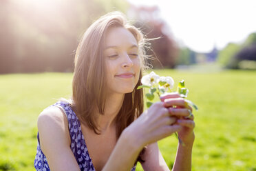 Smiling young woman in a park holding flowers - GIOF04281