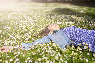 Entspannte junge Frau auf einer Blumenwiese in einem Park liegend - GIOF04283