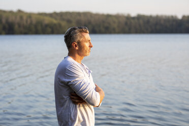 Nachdenklicher Mann steht am See und schaut in die Ferne - FMKF05215