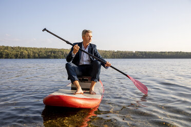 Geschäftsmann paddelt auf einem See - FMKF05222