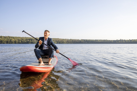 Geschäftsmann paddelt auf einem See, lizenzfreies Stockfoto