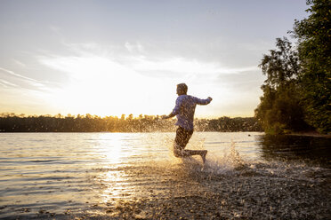 Mann läuft bei Sonnenuntergang in den See - FMKF05238