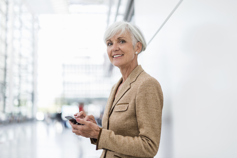 Porträt einer lächelnden älteren Geschäftsfrau, die ein Mobiltelefon benutzt, lizenzfreies Stockfoto