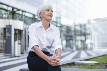 Lächelnde ältere Geschäftsfrau, die draußen sitzt und sich umschaut - DIGF05033