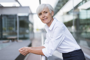 Portrait of confident senior woman leaning on railing in the city - DIGF05044