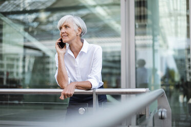 Senior businesswoman leaning on railing in the city talking on cell phone - DIGF05048