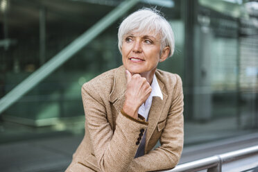 Portrait of senior businesswoman leaning on railing in the city looking around - DIGF05056