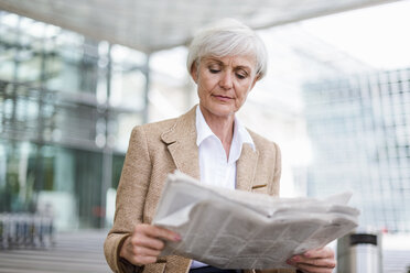 Senior businesswoman in the city reading newspaper - DIGF05059