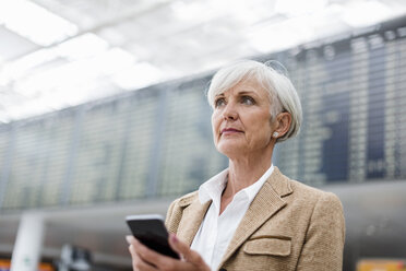 Ältere Geschäftsfrau mit Handy in der Hand am Flughafen - DIGF05065
