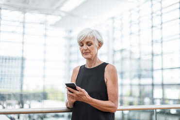 Senior woman standing at railing using cell phone - DIGF05067