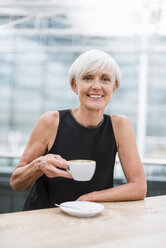 Porträt einer lächelnden älteren Frau, die einen Kaffee trinkt - DIGF05077