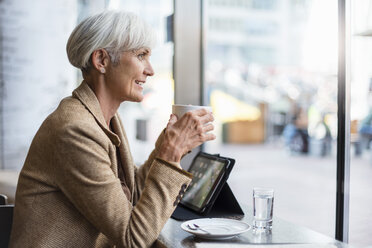 Lächelnde ältere Geschäftsfrau mit Tablet in einem Cafe - DIGF05106