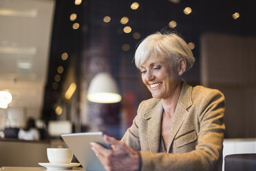 Lächelnde ältere Geschäftsfrau mit Tablet in einem Café - DIGF05110