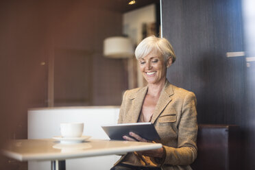 Lächelnde ältere Geschäftsfrau mit Tablet in einem Café - DIGF05111