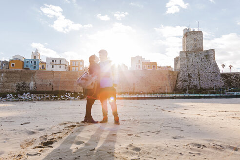 Italien, Molise, Termoli, junges Paar am Strand bei Sonnenaufgang - FLMF00019