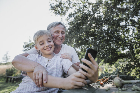 Glückliche Großmutter und Enkel machen ein Selfie im Garten - KMKF00531
