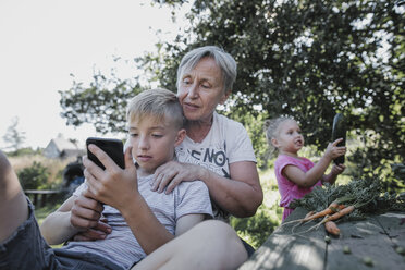 Großmutter mit Enkelkindern im Garten - KMKF00533