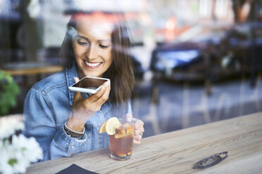 Lächelnde junge Frau telefoniert in einem Café und trinkt Tee - BSZF00568