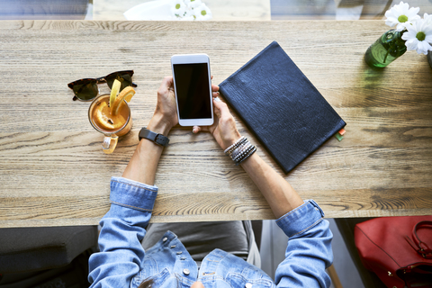 Draufsicht auf eine Frau, die in einem Café einen Tee trinkt und telefoniert, lizenzfreies Stockfoto