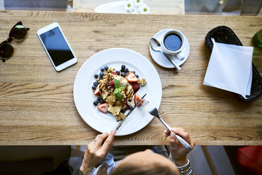 Overhead view of woman eating pancakes in cafe - BSZF00573