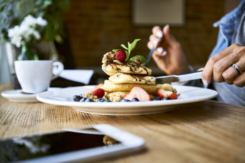 Close-up of woman eating pancakes in cafe - BSZF00574