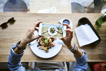 Overhead view of woman taking smartphone picture of pancakes in cafe - BSZF00575