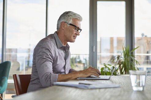 Mature man using laptop on table at home - RBF06497