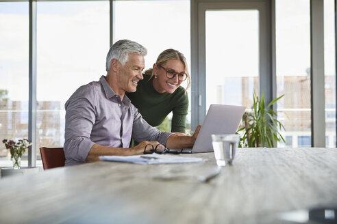 Smiling mature couple using laptop on table at home - RBF06500