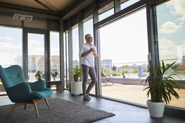 Nachdenklicher reifer Mann mit Kaffeetasse am Fenster stehend zu Hause - RBF06521