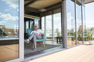 Mature man relaxing in armchair at roof terrace at home - RBF06524