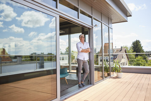 Mature man relaxing standing at roof terrace at home - RBF06525