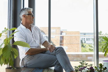 Pensive mature man sitting at the window at home - RBF06534