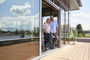 Smiling mature couple standing at roof terrace at home - RBF06535