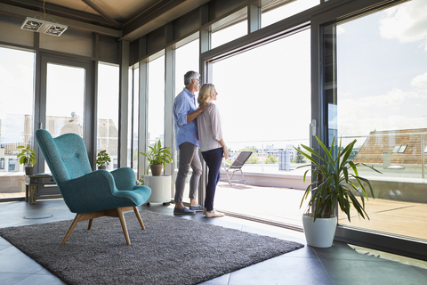 Älteres Paar schaut zu Hause aus dem Fenster, lizenzfreies Stockfoto