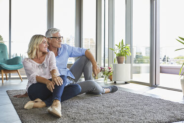 Mature couple relaxing at home looking out of window - RBF06554