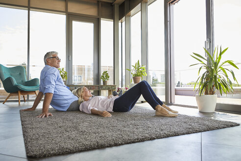 Mature couple relaxing at home looking out of window - RBF06556