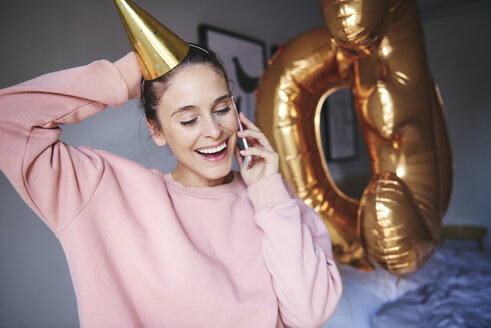 Frau mit Partyhut benutzt Mobiltelefon - ABIF00981