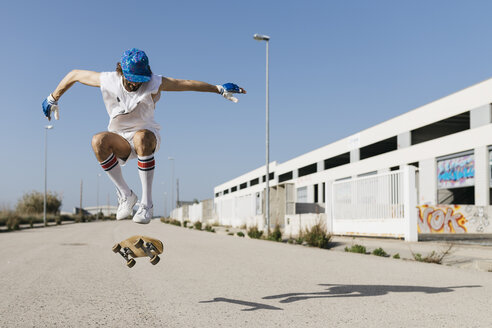 Sportlicher Mann, der mit einem Skateboard über den Boden springt und einen Trick vorführt - JRFF01846