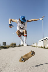 Sportive man jumping above ground with skateboard performing trick - JRFF01847