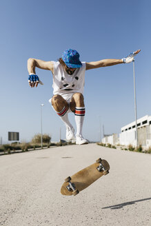 Sportlicher Mann, der mit einem Skateboard über den Boden springt und einen Trick vorführt - JRFF01847