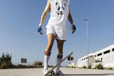 Man in stylish sportive outfit standing on skateboard upside down against blue sky - JRFF01848