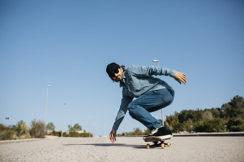 Trendiger Mann in Jeans und Mütze beim Skateboarden - JRFF01861