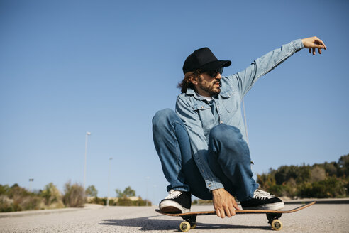 Trendiger Mann in Jeans und Mütze beim Skateboarden - JRFF01862