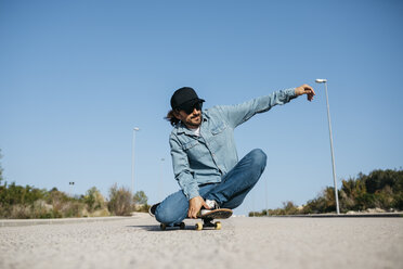 Trendiger Mann in Jeans und Mütze beim Skateboarden - JRFF01863