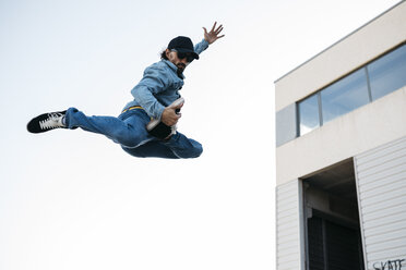 Trendy man in denim and cap doing jump - JRFF01867
