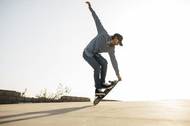 Trendy Mann in Jeans und Mütze Skateboard fahren, stehend auf Skateboard - JRFF01869