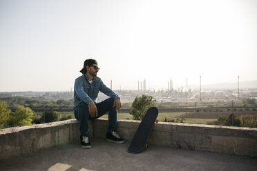 Skateboarder dressed in casual clothes resting at sunset - JRFF01872