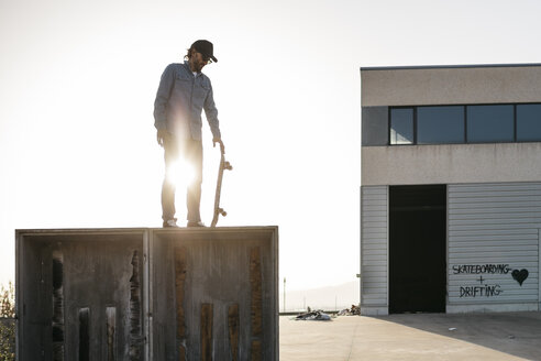 Skateboarder in Freizeitkleidung auf einer Holzkiste, bereit zum Sprung - JRFF01873