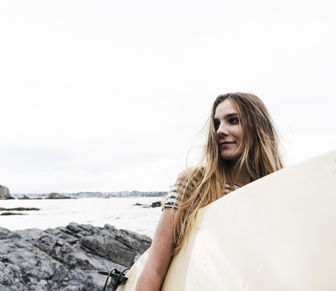 Junge Frau am Strand mit Surfbrett, Porträt, lizenzfreies Stockfoto