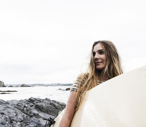 Junge Frau am Strand mit Surfbrett, Porträt - UUF15044
